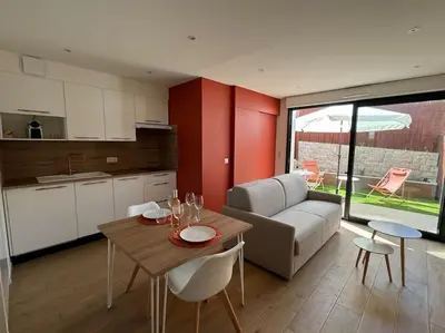 a kitchen and living room with a table and a couch at Studio avec jardinet proche mer in Cagnes-sur-Mer