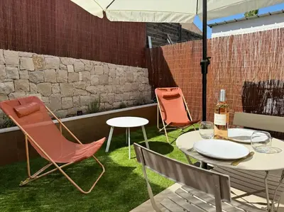 a patio with chairs and tables and an umbrella at Studio avec jardinet proche mer in Cagnes-sur-Mer