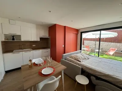 a room with a bed and a table and a kitchen at Studio avec jardinet proche mer in Cagnes-sur-Mer