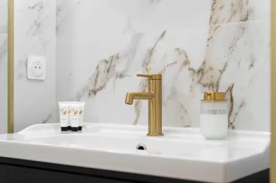 a bathroom sink with a gold faucet and a cup at Nice Renting - VERDI - Apartment Charm & Comfort & AirCon in Nice