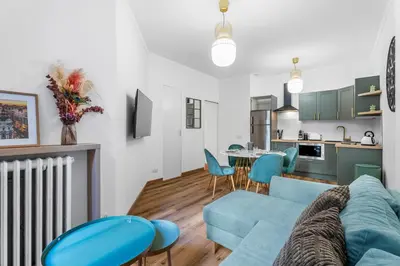 a living room with a blue couch and a kitchen at Nice Renting - VERDI - Apartment Charm & Comfort & AirCon in Nice