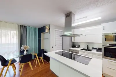 a kitchen with white cabinets and a table and chairs at Cozy Apt with Balcony - 5 min to the Beach in Nice
