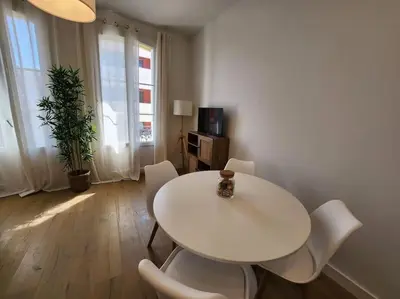 a white dining room with a white table and chairs at Nice Fac St Jean D'Angely in Nice