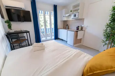 a bedroom with a large white bed and a kitchen at Studios cosy Nice in Nice