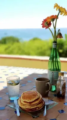 a table with a plate of pancakes and a vase with flowers at Eze flat with terrace sea view and mountain view in Èze
