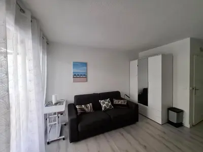 a living room with a black couch and a white wall at Tournesol de Nice in Nice