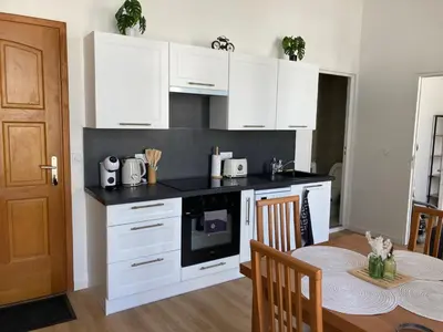 a kitchen with white cabinets and a table with a dining room at LocaNice Masséna in Nice