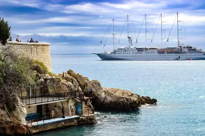 a cruise ship in the water next to a cliff at Duplex moderne port de Nice in Nice