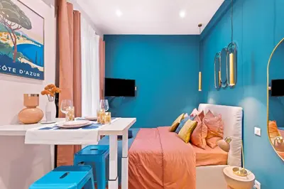 a room with blue walls and a table and a bed at Nice Renting - SPITALIERI - Chic & Cosy Art Deco Nest Nice Étoile in Nice