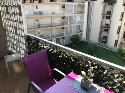 a balcony with a table and purple chairs and a building at Royal Promenade in Nice