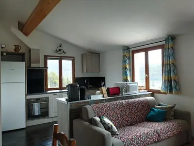a living room with a couch and a kitchen at entre terre et mer 3 pièces in Gattières