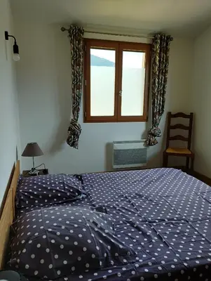 a bedroom with a bed and a window and a chair at entre terre et mer 3 pièces in Gattières