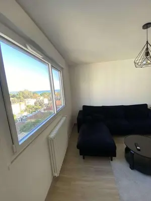 a living room with a couch and a large window at Proche promenade des anglais in Nice