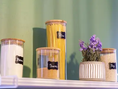 a shelf with three jars of pasta and a vase with flowers at Pause et Sérénité Studio de 28m2 in Cagnes-sur-Mer