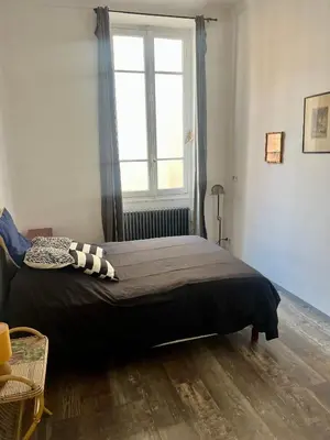 a bed in a room with a large window at Appartement le Fighiéra in Nice