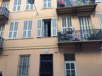 a building with white windows and a balcony at Appartement le Fighiéra in Nice