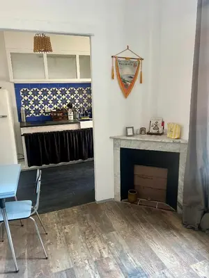 a room with a fireplace and a table and a chair at Appartement le Fighiéra in Nice