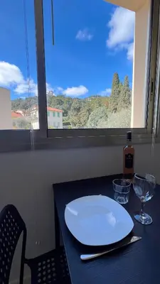 a table with a white plate and a window at Beau studio au cœur de Beaulieu-sur-mer in Beaulieu-sur-Mer