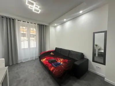 a living room with a black couch and a mirror at Appartement 3 pieces proche du Negresco in Nice