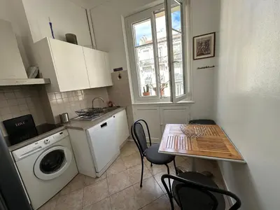 a kitchen with a washing machine and a table with chairs at Beau T2 proche Negresco in Nice