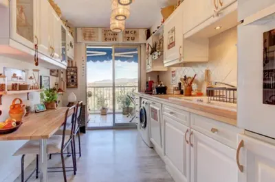 a large kitchen with a table and a counter top at Terrasses de la Corniche, 2p 65m2 spacieux, terrasses mer & montagne, piscine et parking privé in Nice