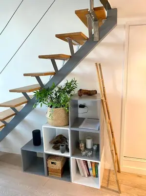 a book shelf under a stairs with a shelf underneath it at Superbe Duplex avec vue ! in Villefranche-sur-Mer