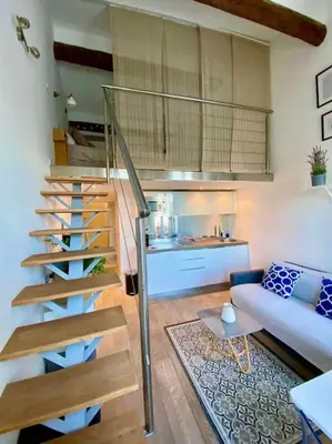 a staircase in a living room with a couch and a kitchen at Superbe Duplex avec vue ! in Villefranche-sur-Mer
