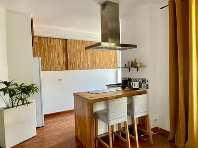 a kitchen with a wooden table and white chairs at Spacieux appartement à Nice in Nice