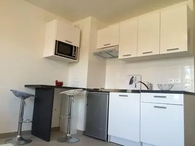 a kitchen with white cabinets and a counter with stools at Ma place au sud Nice 405 in Nice
