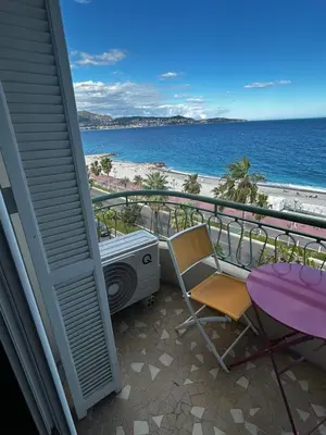 a balcony with a table and a chair and the beach at Sea Front View - FRONT DE MER ET VUE PANORAMIQUE in Nice