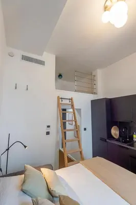 a room with a bed and a kitchen with a ladder at Charmant appartement rénové au cœur de Nice in Nice