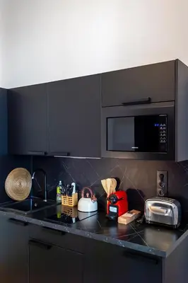 a kitchen with a black counter top with a microwave at Charmant appartement rénové au cœur de Nice in Nice