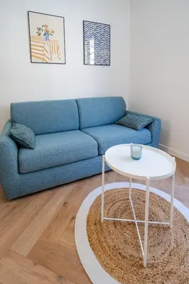 a living room with a blue couch and a white table at Studio hypercentre de Nice climatisé in Nice