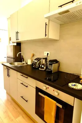 a kitchen with white cabinets and a black counter top at Studio au coeur du Vieux Nice - Vue mer et clocher in Nice