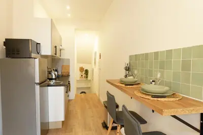 a kitchen with a counter with two sinks and a refrigerator at Studio au coeur du Vieux Nice - Vue mer et clocher in Nice