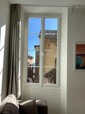 a room with a window with a couch and a building at Studio au coeur du Vieux Nice - Vue mer et clocher in Nice