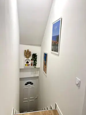 a hallway with a staircase with a white wall at Studio au coeur du Vieux Nice - Vue mer et clocher in Nice