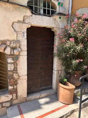 a wooden door in the side of a building with flowers at Studio climatisé Bohème Chic in Villefranche-sur-Mer