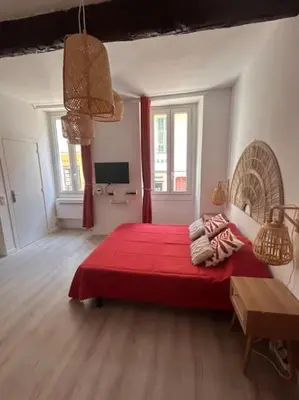 a bedroom with a red bed with a red blanket at Studio climatisé Bohème Chic in Villefranche-sur-Mer
