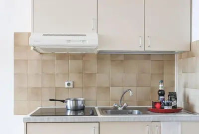 a kitchen with white cabinets and a sink at Résidence Partenaire Le Palais de la Marine in Villefranche-sur-Mer