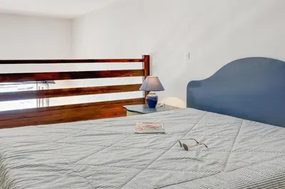a bedroom with a bed with a book and a lamp at Résidence Partenaire Le Palais de la Marine in Villefranche-sur-Mer