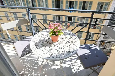 a table with a vase of flowers on a balcony at Appartement Gare Nice Ville in Nice