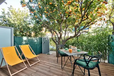 a table and chairs on a deck with an orange tree at Studio avec grande terrasse YourHostHelper in Villefranche-sur-Mer