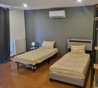 a room with two beds and a heater on the wall at F2 ou F3 ,appartement climatisé neuf, magnifique vue sur mer et aéroport, proche tram et gare sncf 1 min,aéroport 3 minutes, 3 rooms, new AC apartment, magnificent sea and airport views, close to tram and SNCF train station 1 min, airport 3 min in Nice