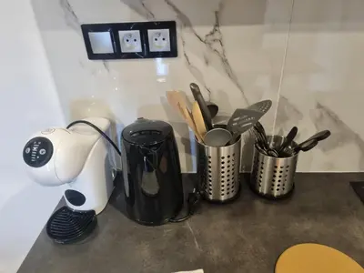 a counter with various utensils and a coffee maker at F2 ou F3 ,appartement climatisé neuf, magnifique vue sur mer et aéroport, proche tram et gare sncf 1 min,aéroport 3 minutes, 3 rooms, new AC apartment, magnificent sea and airport views, close to tram and SNCF train station 1 min, airport 3 min in Nice