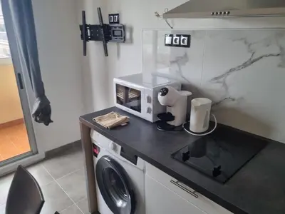 a kitchen with a washing machine and a microwave at F2 ou F3 ,appartement climatisé neuf, magnifique vue sur mer et aéroport, proche tram et gare sncf 1 min,aéroport 3 minutes, 3 rooms, new AC apartment, magnificent sea and airport views, close to tram and SNCF train station 1 min, airport 3 min in Nice