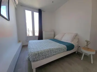 a white bedroom with a bed and a window at Appt 2 pièces 43 Avenue Jean Médecin in Nice