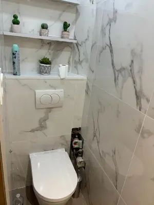 a bathroom with a toilet and a marble wall at APPARTEMENt COSY in Nice