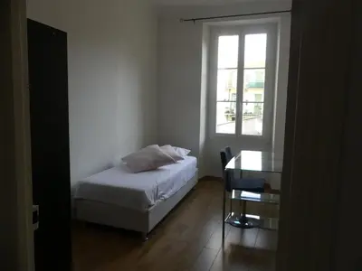 a bedroom with a bed and a desk and a window at 68 m2 central pour des vacances en famille in Nice