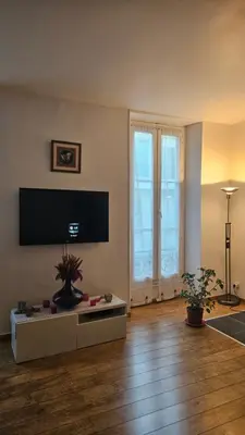 a living room with a tv and a table at 68 m2 central pour des vacances en famille in Nice